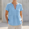 Blue women's V-neck peplum blouse with pintuck detailing and curved hem by FJØRNA, shown on a model.
