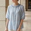 Blue FJØRNA summer linen blouse for women with ruffle details, lightweight and stylish top perfect for warm weather.