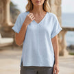 Blue FJØRNA women's summer blouse with V-neck and short sleeves, made of denim fabric, perfect for casual warm-weather wear.