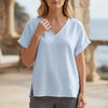 Blue FJØRNA women's summer blouse with V-neck and short sleeves, made of denim fabric, perfect for casual warm-weather wear.