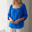 Blue women's V-neck linen summer blouse by FJØRNA featuring a flowy, lightweight design and relaxed fit.