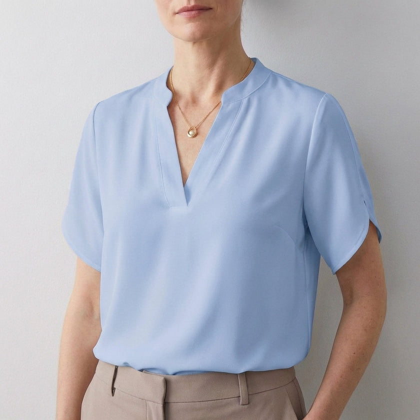 FJØRNA women's summer blouse with V-neck, short sleeves, flowy blue fabric, stylish and lightweight top for warm weather.
