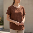 FJØRNA women's short sleeve linen summer blouse in brown with an asymmetric design, stylish and breathable for warm weather.