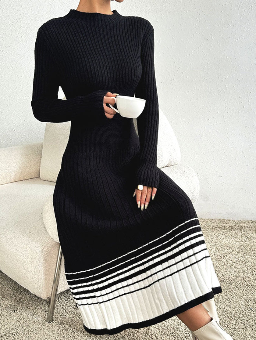 FJØRNA pleated black and white striped sweater dress, stylish and comfortable, shown on a model against a neutral background.