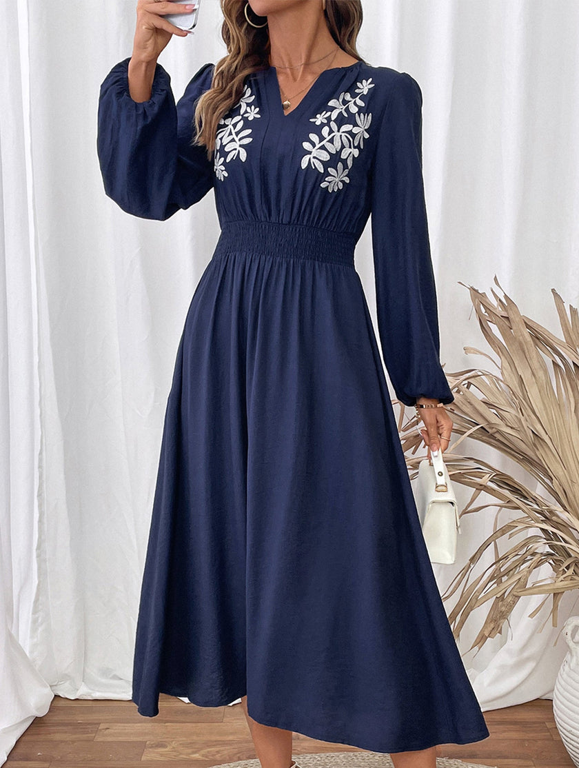 Light blue embroidered waist V-neck dress by FJØRNA, featuring elegant details and a flattering fit, shown on a model.
