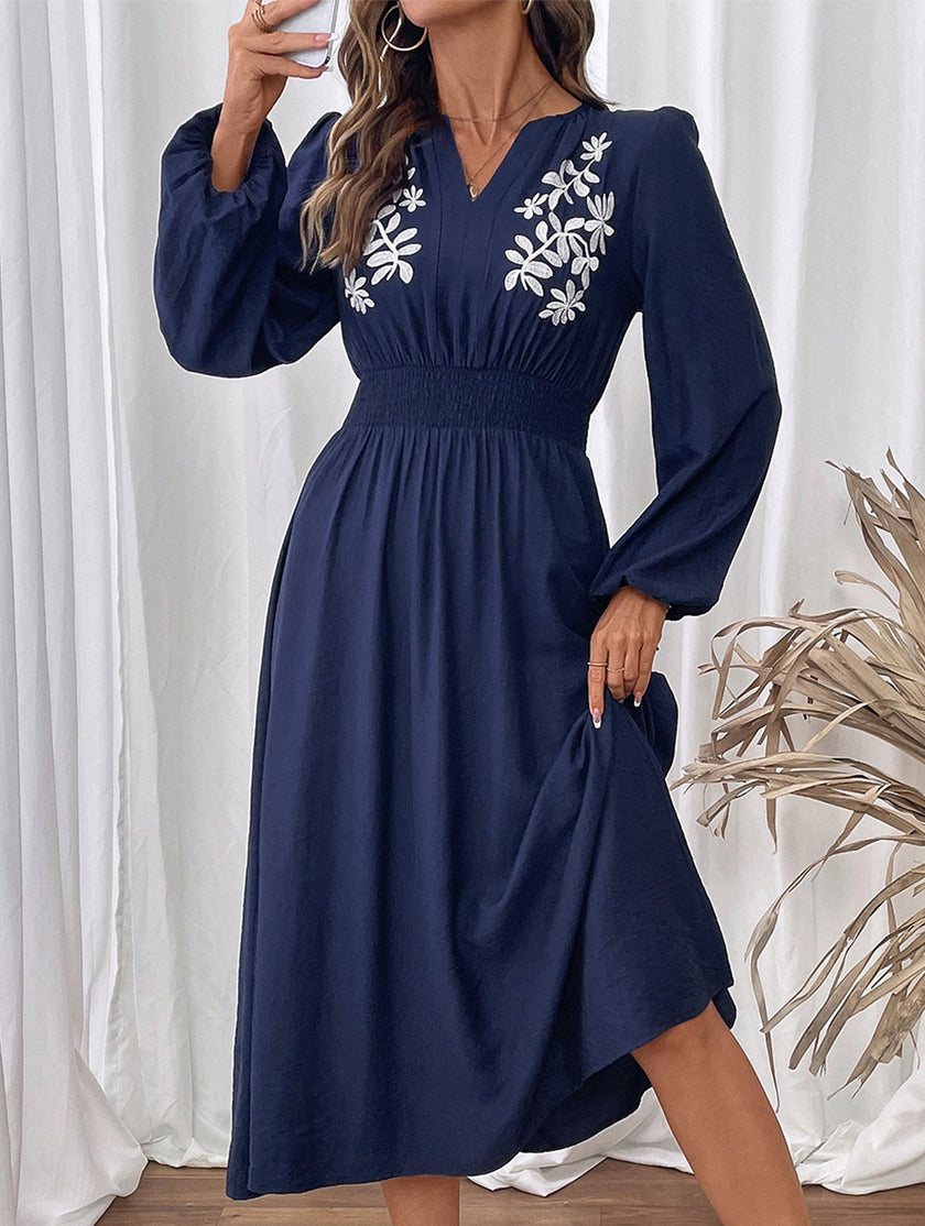 Light blue embroidered waist V-neck dress by FJØRNA, showcasing intricate embroidery and flowing fabric.