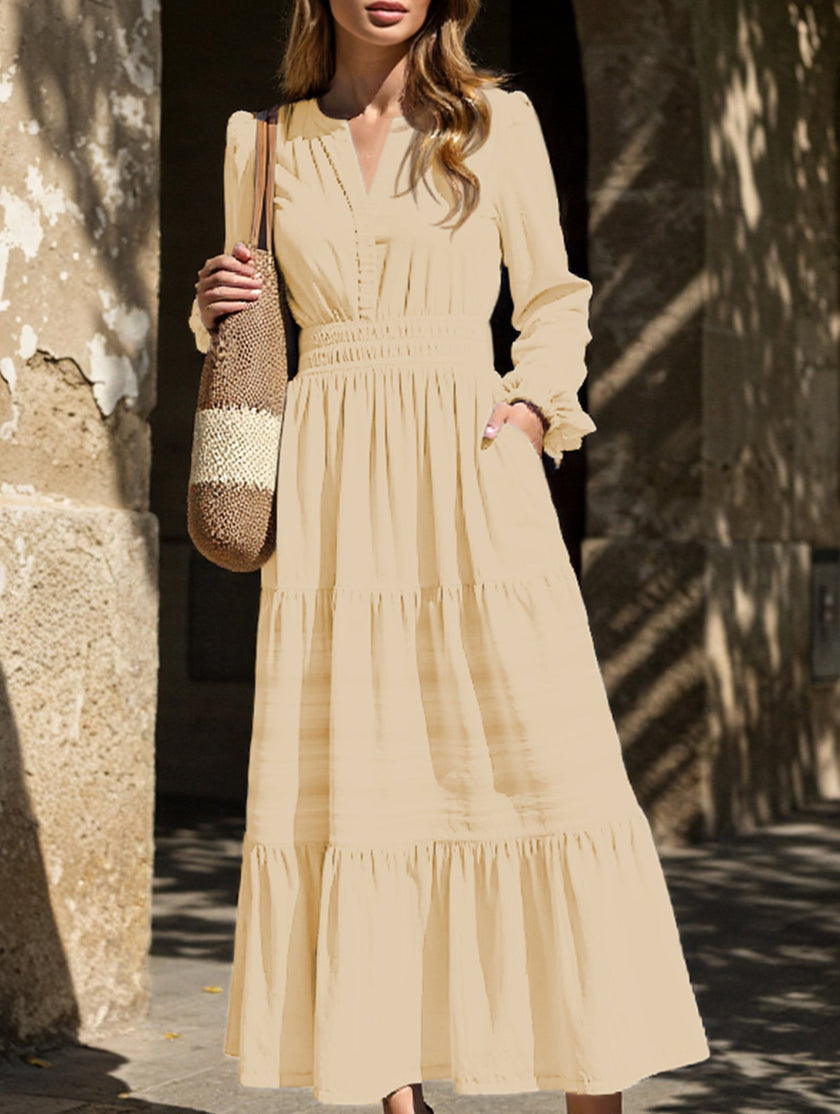 FJØRNA white V-neck pleated waist tiered long-sleeved dress displayed on a hanger, showcasing its elegant design and fabric details.