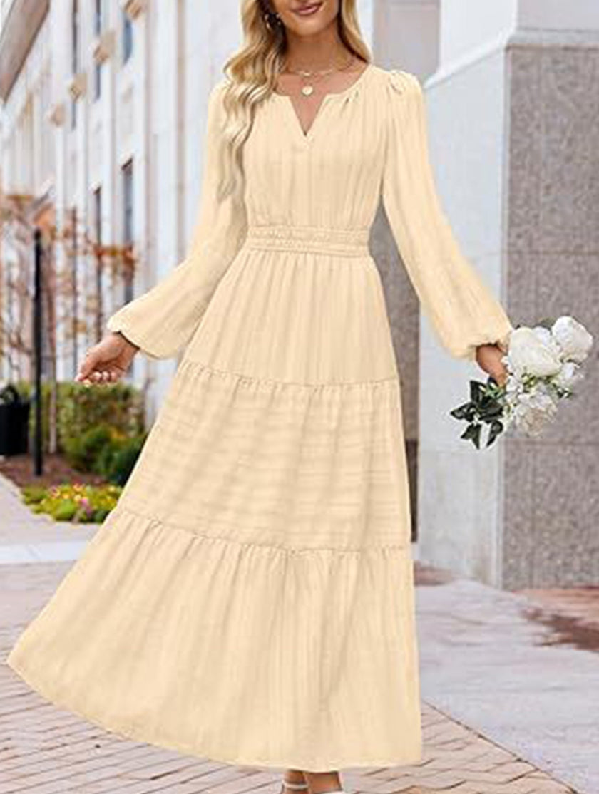 FJØRNA beige V-neck pleated waist tiered long-sleeved dress displayed on a hanger, showcasing elegant design and flowy fabric.