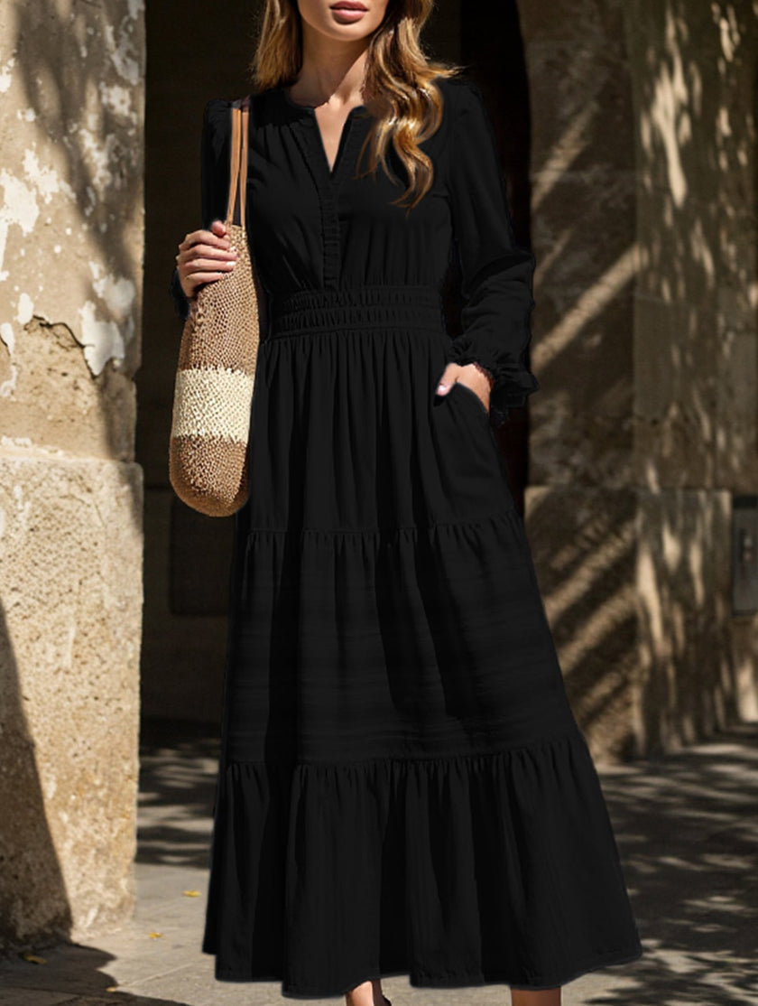 Black V-neck pleated waist tiered long-sleeved dress by FJØRNA, showing the flowing fabric and elegant design.