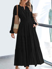 Black V-neck pleated waist tiered long-sleeved dress by FJØRNA, featuring a flowing silhouette and elegant design.