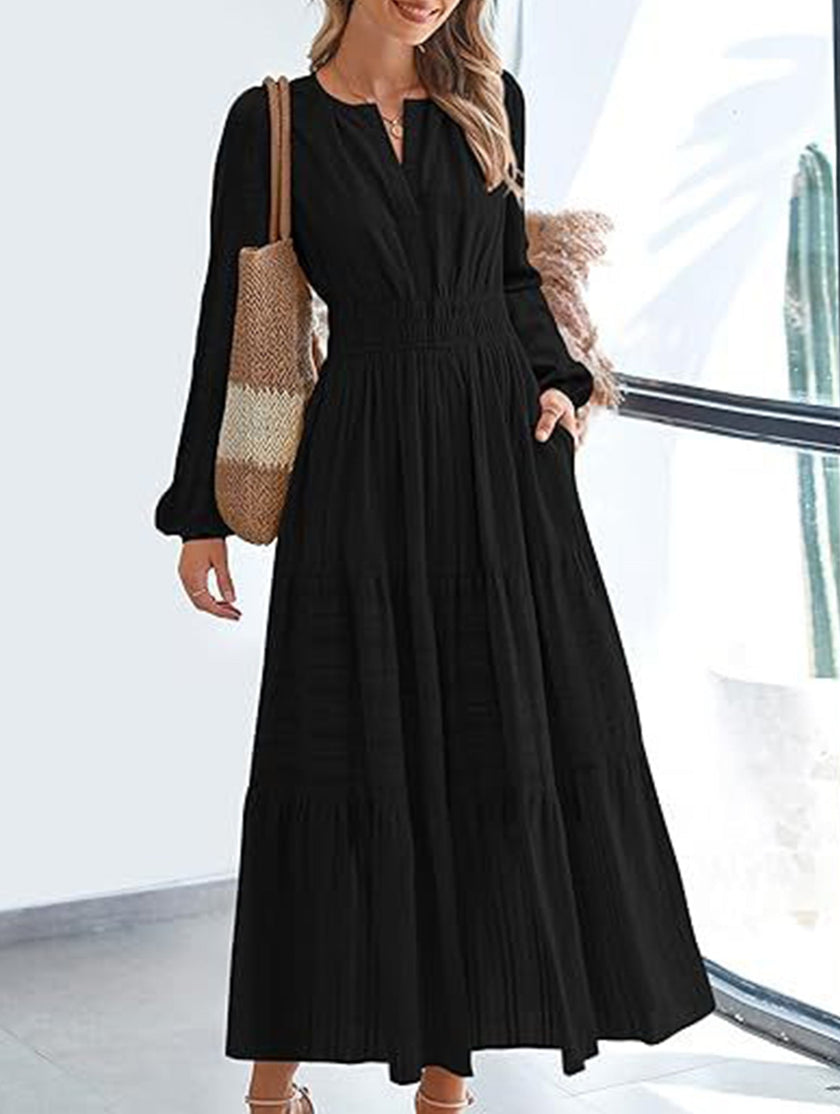 Black V-neck pleated waist tiered long-sleeved dress by FJØRNA, featuring a flowing silhouette and elegant design.