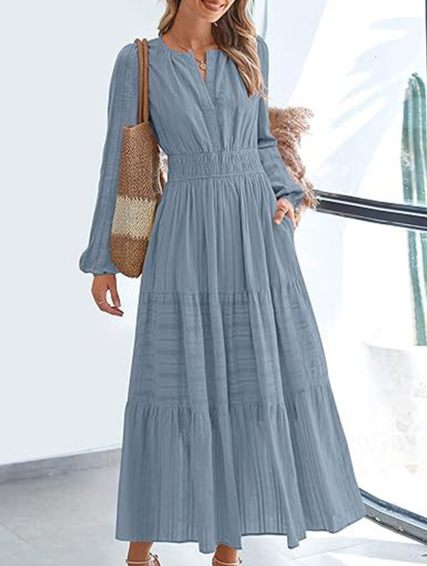FJØRNA blue-grey V-neck pleated waist tiered long-sleeved dress, elegant and flowy for stylish occasions.