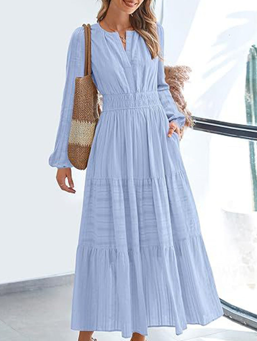 Light blue V-neck pleated waist tiered long-sleeved dress by FJØRNA, featuring a flowing design and elegant silhouette.