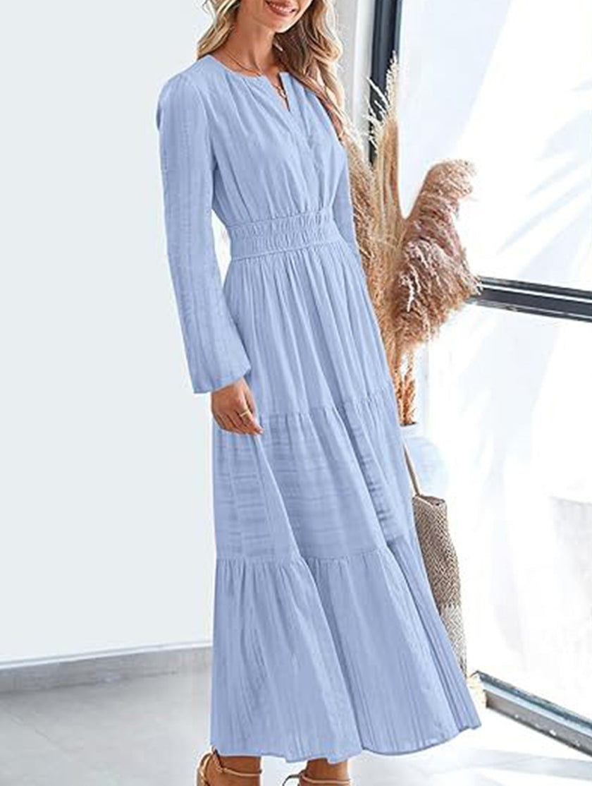 Light blue V-neck pleated waist tiered long-sleeve dress by FJØRNA, featuring a flowing silhouette and elegant design.