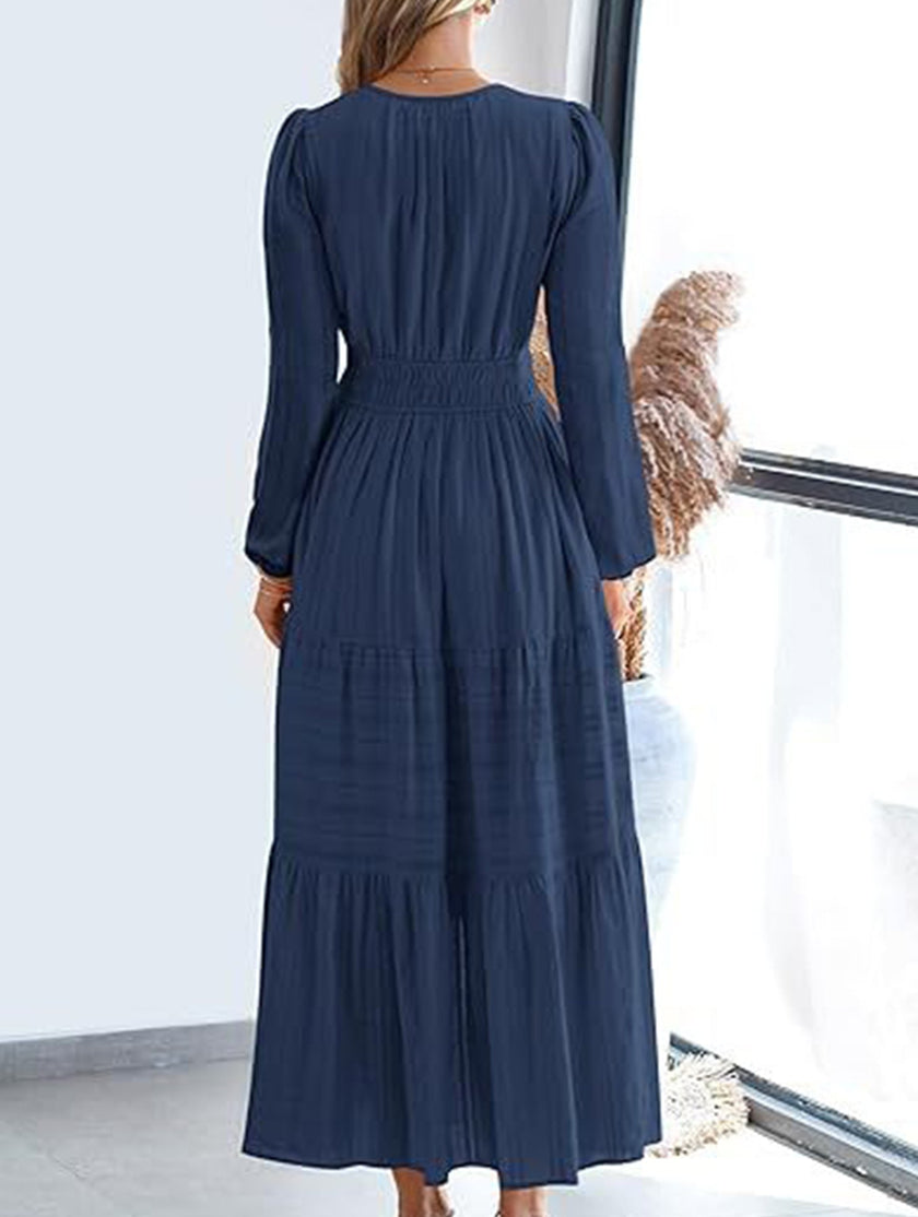 FJØRNA navy V-neck pleated waist tiered long-sleeved dress, elegant and flowing with layered design and classic silhouette.