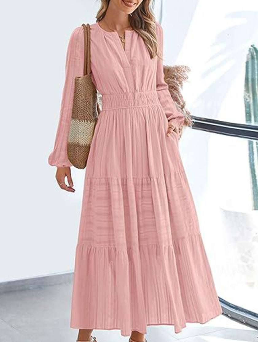 White V-neck pleated waist tiered long-sleeved dress by FJØRNA, featuring flowing fabric and elegant design.