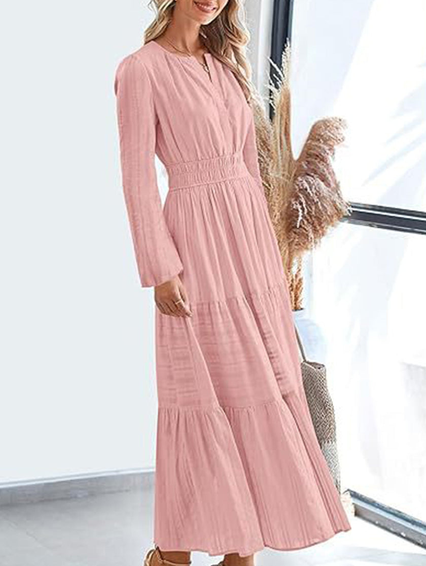 FJØRNA white V-neck pleated waist tiered long-sleeved dress with flowing fabric and elegant design, shown on a model.