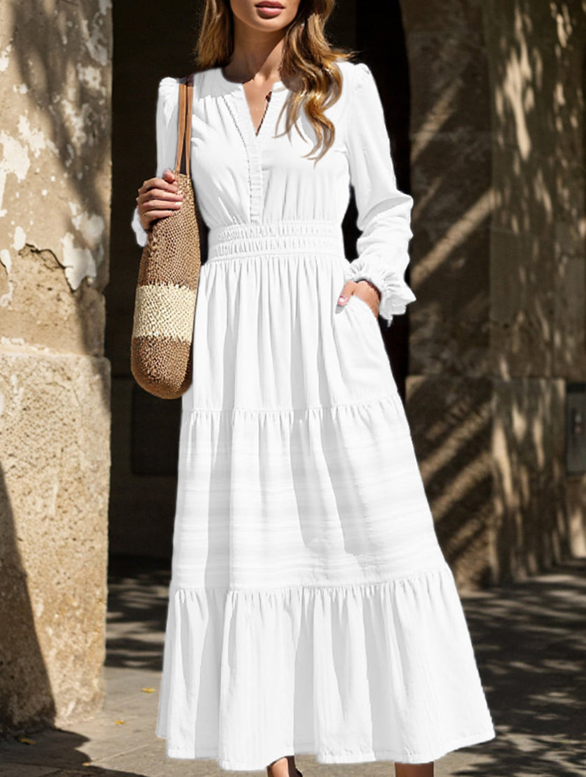 White V-neck pleated waist tiered long-sleeved dress by FJØRNA, featuring a flowing silhouette and elegant design.