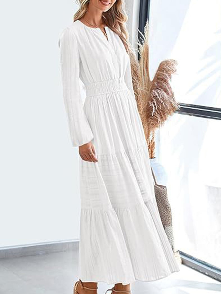White FJØRNA V-neck pleated waist tiered long-sleeved dress with flowing fabric and elegant design.