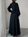 White FJØRNA long-sleeved dress with a simple, elegant design, shown hanging on a wooden hanger.