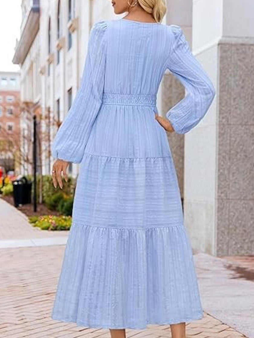FJØRNA white V-neck tiered puff sleeve maxi dress, stylish and flowing, shown in light blue in the image.