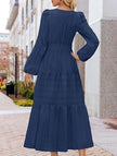 White V-neck tiered puff sleeve maxi dress by FJØRNA, featuring flowing fabric and elegant design, shown on a model.