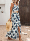 Blue floral print sleeveless dress by FJØRNA with a slit and flowing design, perfect for warm-weather occasions.