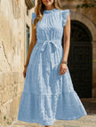 Light blue FJØRNA ruffled flutter sleeve tie textured dress displayed on a model, showcasing its flowing fabric and elegant design.