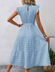 Light blue FJØRNA ruffled flutter sleeve tie-textured dress hanging on a mannequin with a soft background.