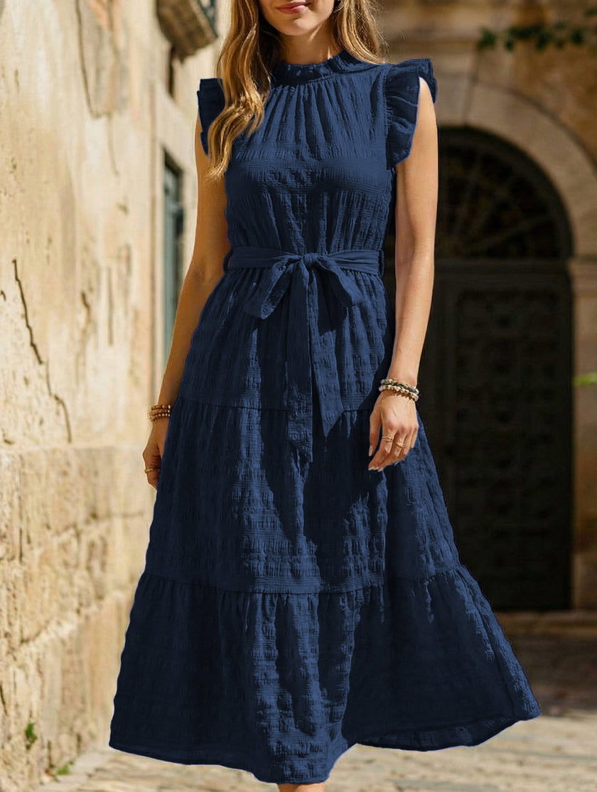 White FJØRNA ruffled flutter sleeve tie textured dress displayed on a model, showcasing its elegant design and fabric details.