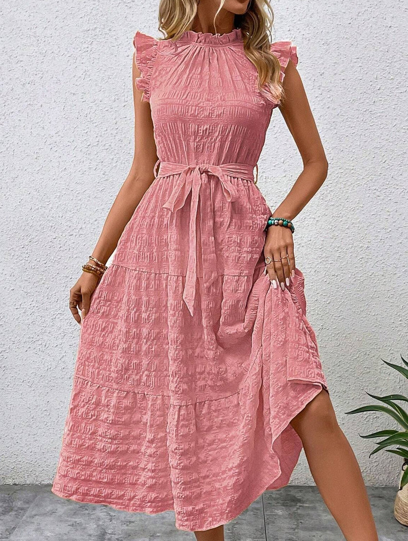 FJØRNA white ruffled flutter sleeve tie textured dress displayed on a mannequin, showcasing its elegant design and fabric details.