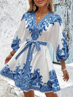 FJØRNA printed white V-neck three-quarter sleeve tie-waist dress displayed on a hanger, showcasing its elegant design and fabric details.