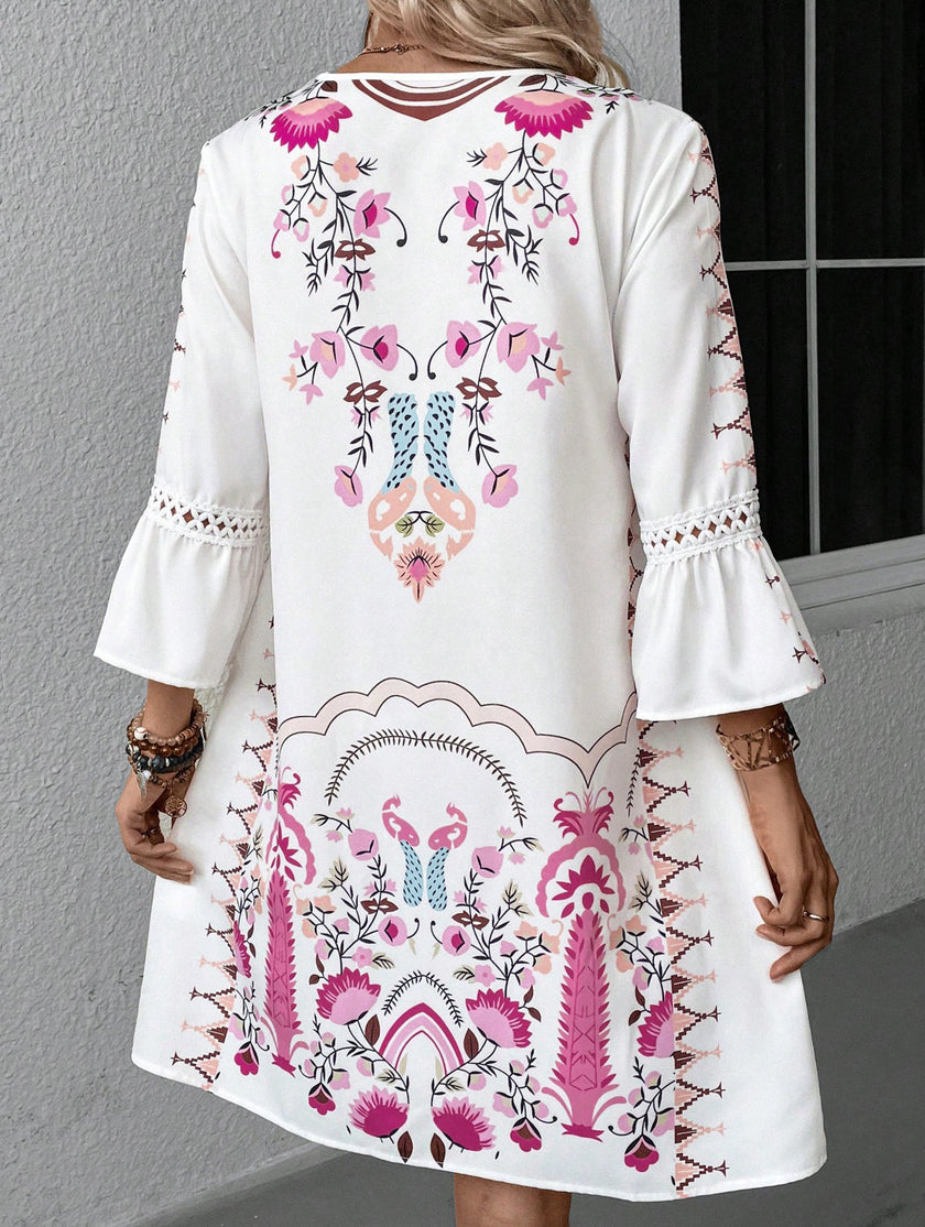 White V-neck lace patch print dress by FJØRNA, showing intricate lace details and a flowing silhouette.