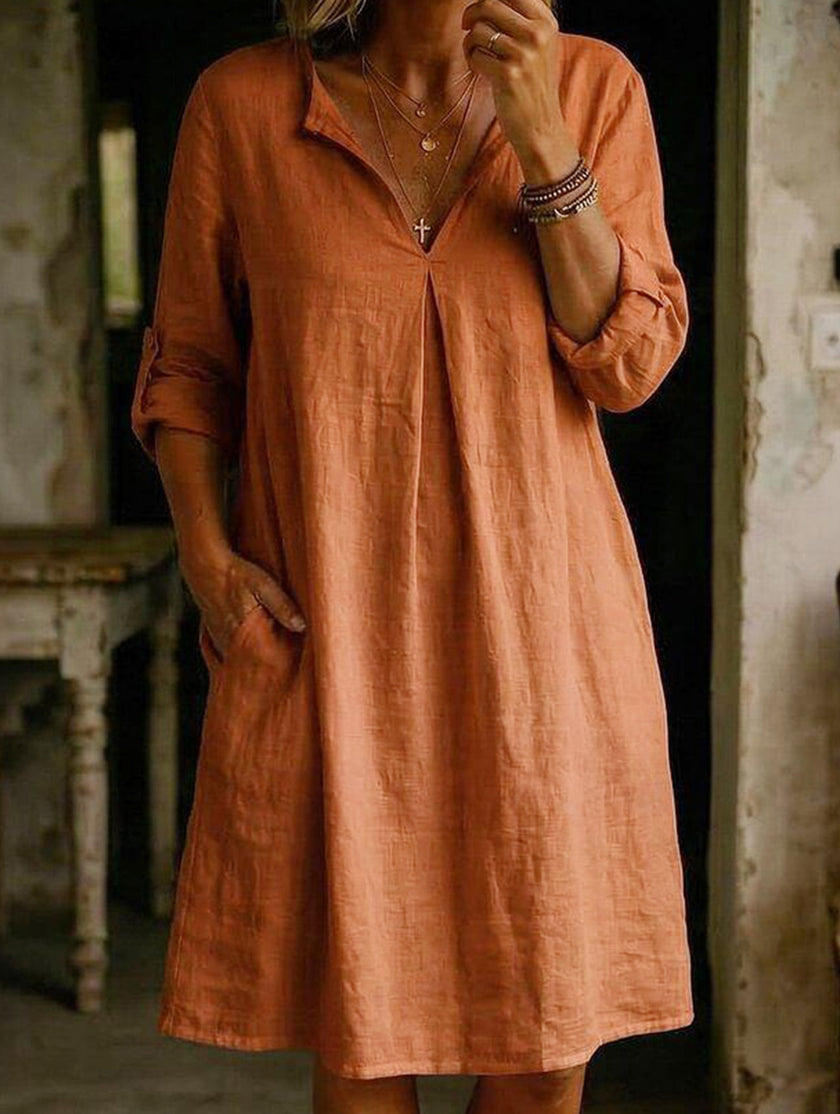 FJØRNA white linen V-neck short sleeve dress displayed on a hanger, showcasing its relaxed fit and lightweight fabric.