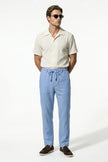 Light blue men's linen trousers by FJØRNA, breathable straight fit summer pants, full-body view.