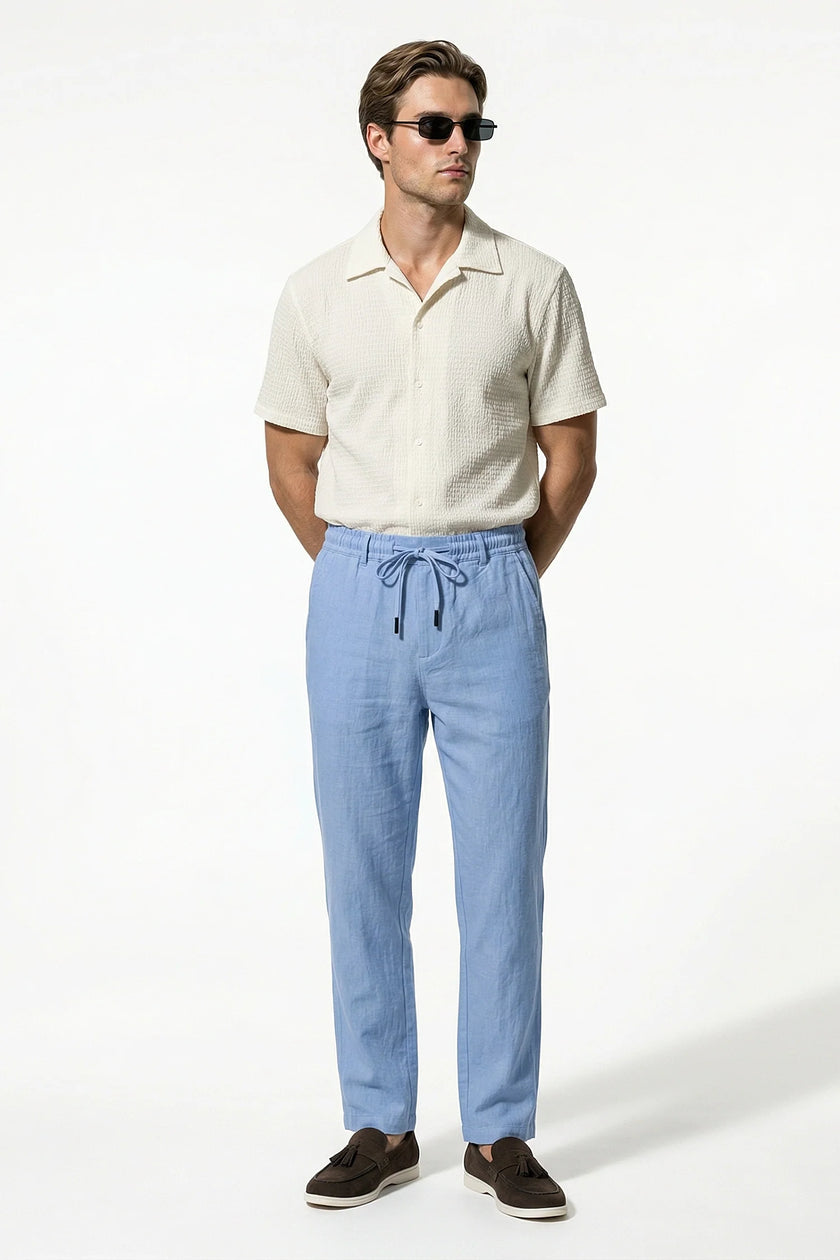 Light blue men's linen trousers by FJØRNA, breathable straight fit summer pants, full-body view.