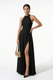 Black FJØRNA sleeveless maxi dress with high neck, A-line silhouette, and side slit, shown full-body on a woman.