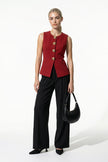Women's deep red sleeveless waistcoat by FJØRNA with tailored fit and metal button details, shown from the front on a model.