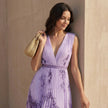 Close-up of FJØRNA pleated A-line maxi dress featuring a V-neck and balloon sleeves.