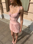 FJØRNA Coquette pleated mini dress with a fitted bodice and flowy skirt, featuring pleated fabric and stylish design.