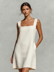 Cream linen sleeveless mini dress by FJØRNA, featuring a simple silhouette and elegant evening dress style.