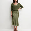 Dark green FJØRNA relaxed V-neck knit top and satin maxi skirt set displayed on a hanger.