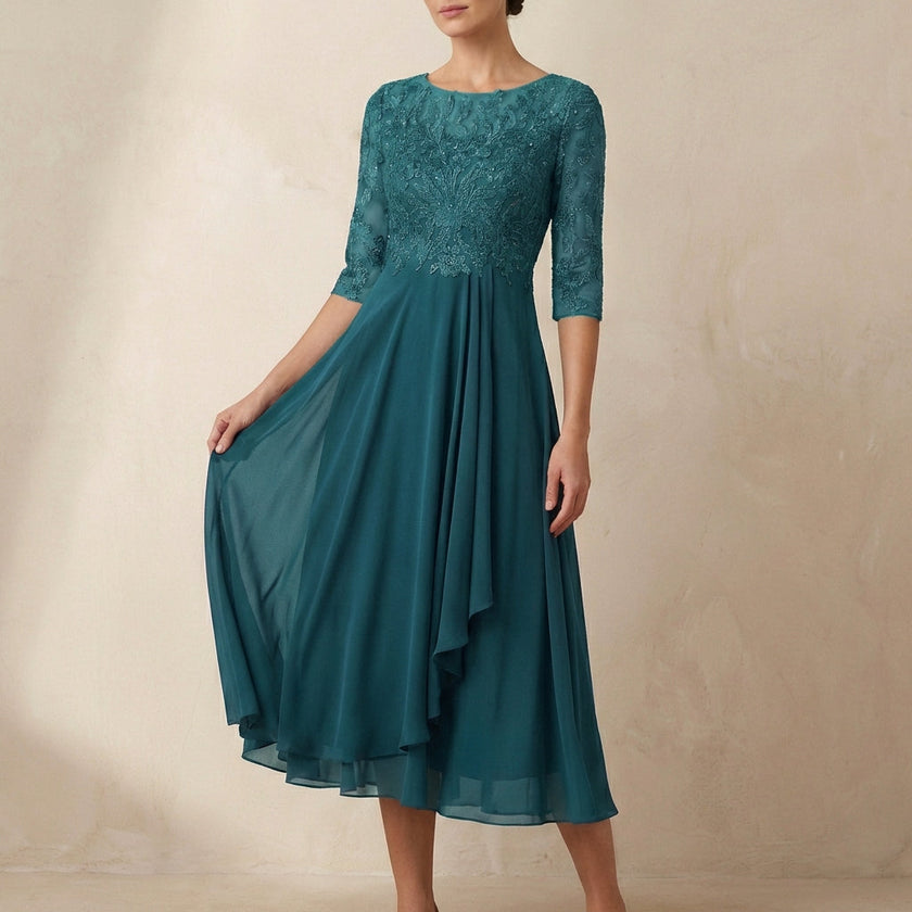 Dark green FJØRNA embroidered A-line midi dress with sheer sleeves and pockets, displayed on a hanger.