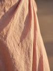 Close-up of FJØRNA women's elegant V-neck linen maxi dress showing textured fabric and detailed stitching.