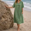 Women's linen beach dress by FJØRNA featuring a casual V-neck, loose fit, and midi length for summer beachwear.