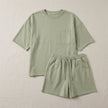 FJØRNA oversized two-piece set with relaxed fit, chest pocket, and wide-leg shorts, laid flat on a surface.