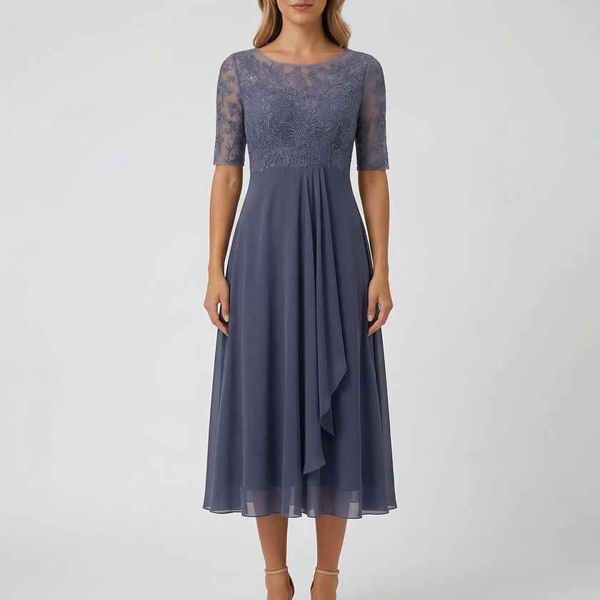 White FJØRNA A-line midi dress with lace bodice, showcasing a flowy skirt and elegant lace details in a stylish dress image.
