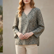 FJØRNA women's summer blouse with V-neck and linen fabric, featuring a slit detail, displayed on a forest-themed background.