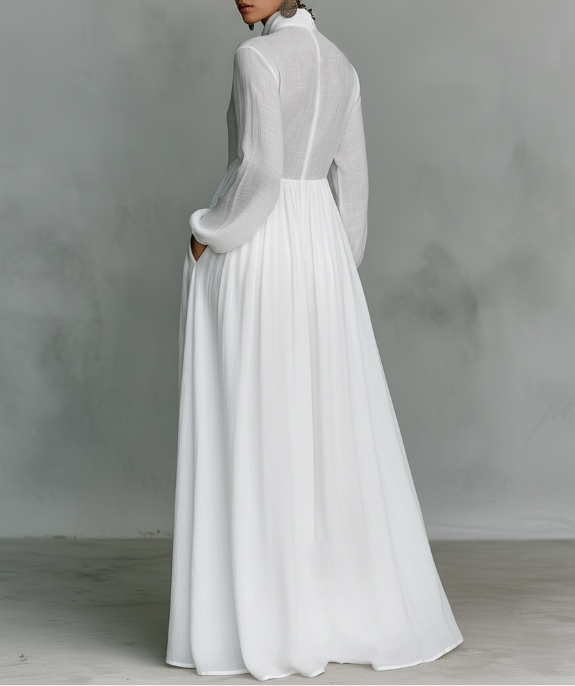 FJØRNA white maxi dress with stand collar, button details, long sleeves, and flowing silhouette for elegant style.