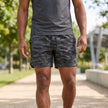 Men's gray camouflage athletic shorts by FJØRNA with adjustable waist, performance woven fabric, and side pockets.
